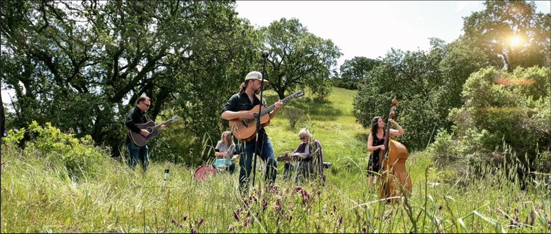 The Lightholder acoustic band performs outdoors on a hillside